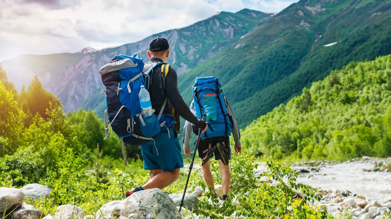 Trekking in mountains. Mountain hiking. Tourists with backpacks hike on rocky way near river. Wild nature with beautiful views. Sport tourism in Svaneti, Georgia. Hikers and climbers in mounts; Shutterstock ID 1183637155